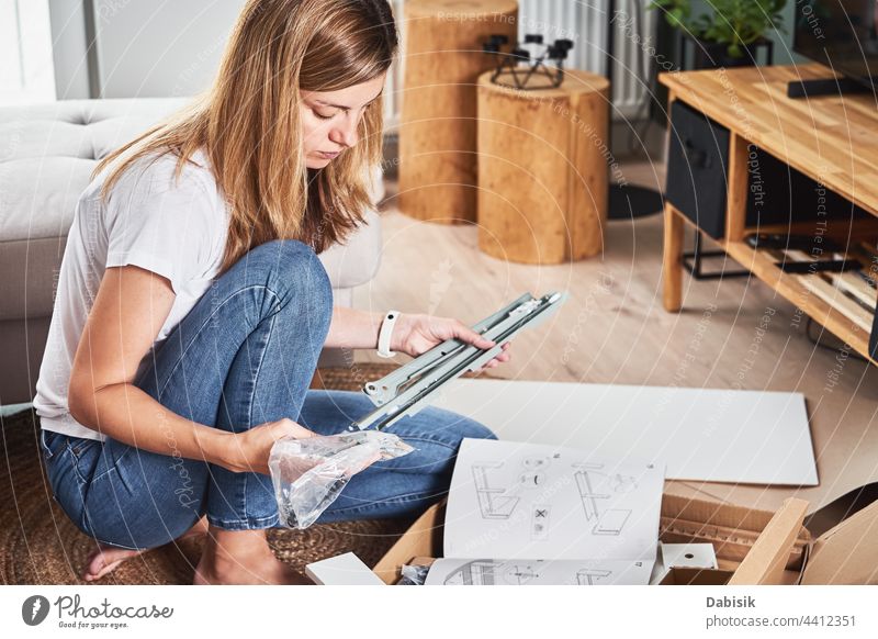 Frau liest Gebrauchsanweisung für den Zusammenbau von Möbeln Belehrung manuell diy Menschen Innenbereich Appartement Versammlung Kasten Kaukasier Gerät fixieren