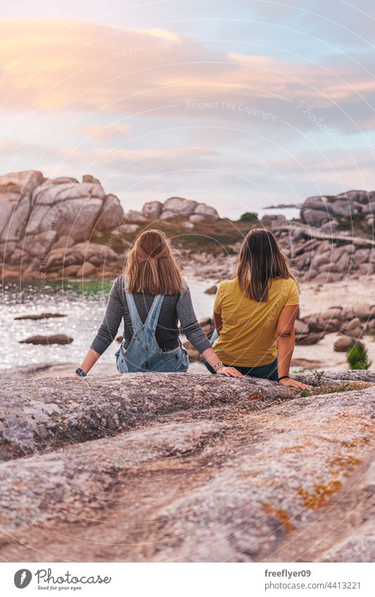 Zwei Freundinnen, die das Meer betrachten Frau Freunde Textfreiraum Kontemplation betrachtend Sonnenuntergang Meeresufer Steine Küstenlinie mediterran Kaukasier