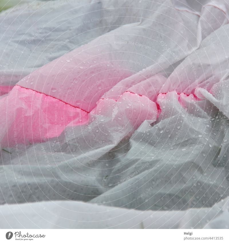 Detailaufnahme der Hülle eines am Boden liegenden Großdrachens mit Regentropfen Drachen Drachenfest Stoff Falten Tropfen nass faltig draußen Wassertropfen