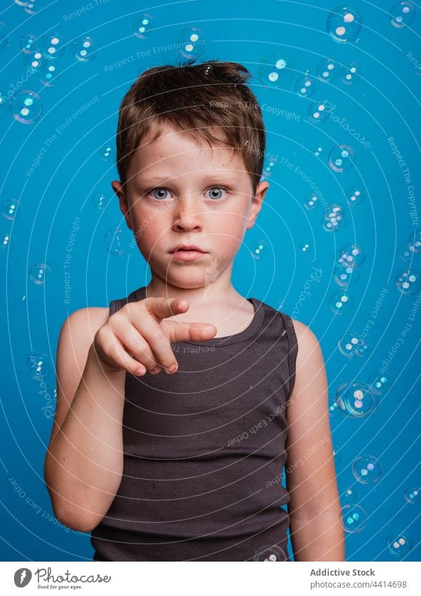 Schockiertes Kind zeigt berührende Geste im Studio mit Seifenblasen gestikulieren Zeigefinger Erstaunen erstaunt Junge Überraschung Kindheit Gesichtsausdruck