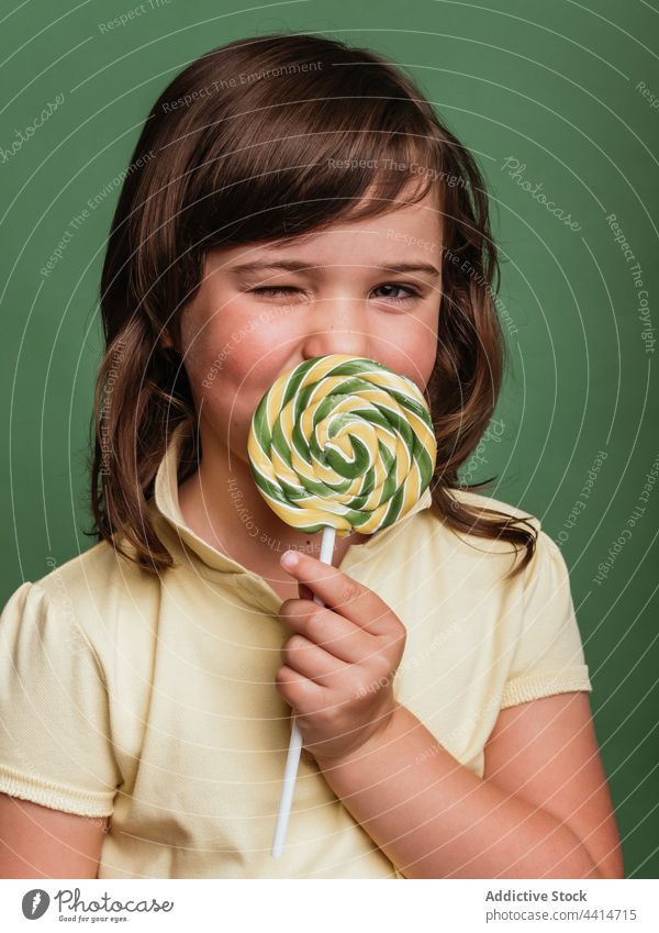 Fröhliches Mädchen mit Spirale Süßigkeiten auf grünem Hintergrund lutschen Lollipop Verwirbelung Bonbon süß lustig ausspannen Kind Dessert niedlich bezaubernd