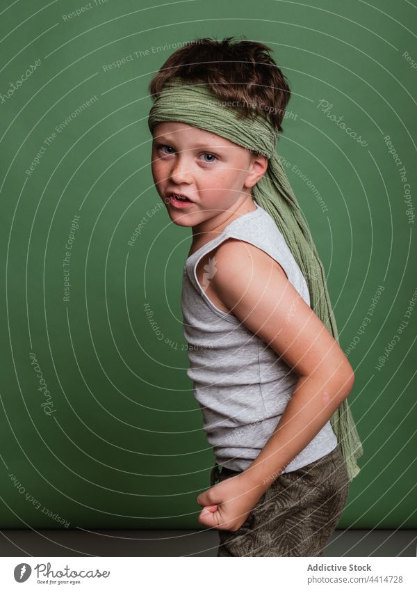 Verspieltes Karate-Kind auf grünem Hintergrund spielen Spiel Junge heiter Spaß haben sich[Akk] melden die Faust ballen Glück Kindheit hachimaki Kopftuch positiv