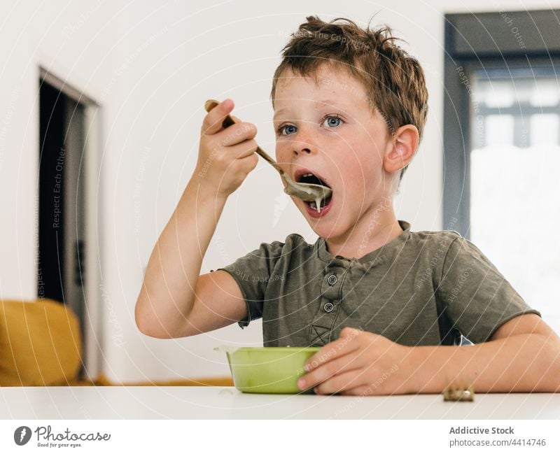 Kind mit Löffel isst Cremesuppe essen lutschen Mittagessen Sahne Suppe Junge offen Mund Mahlzeit Lebensmittel heimwärts Speise geschmackvoll Küche niedlich