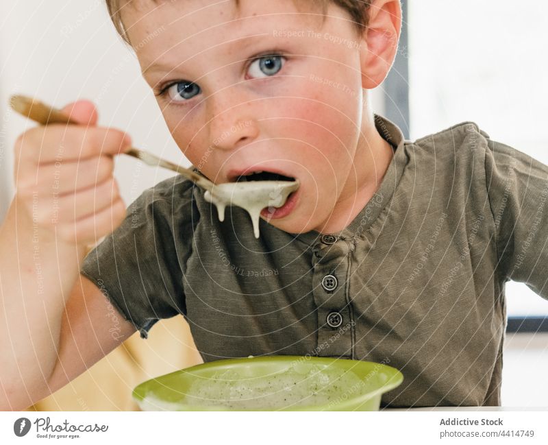 Lustiges Kind mit schmutzigem Mund beim Mittagessen zu Hause dreckig Lebensmittel Junge Mahlzeit lustig Schalen & Schüsseln Tisch sitzen Kindheit unordentlich