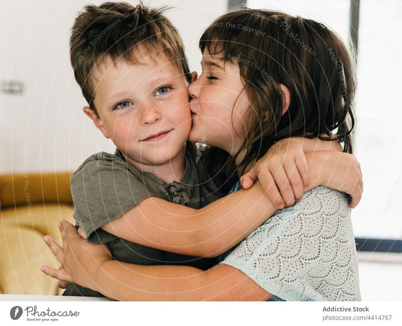 Entzückte Zwillinge, die sich zu Hause umarmen und küssen Kinder Umarmung Zusammensein Kuss heimwärts Geschwisterkind Schwester Bruder Bonden Angebot Glück