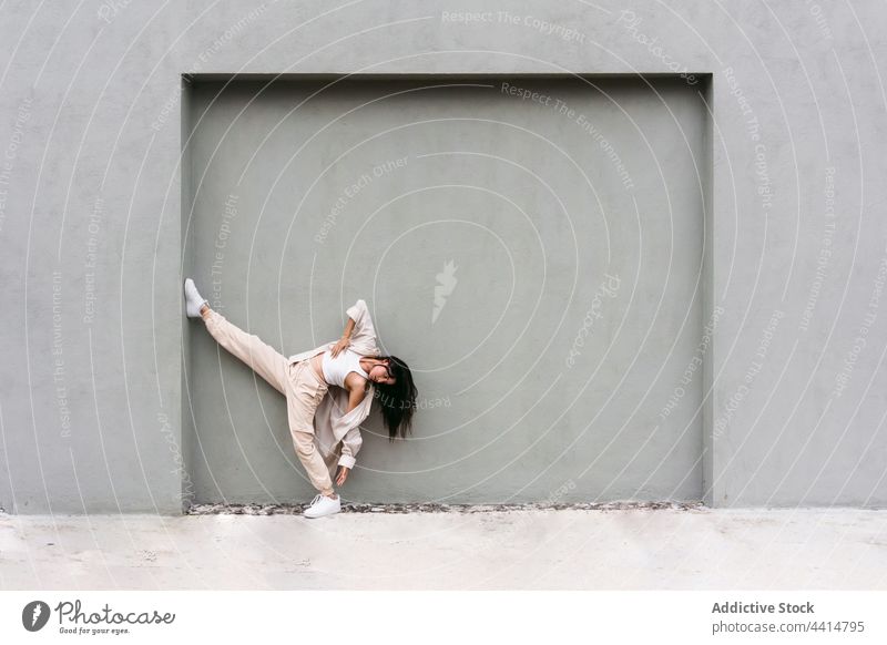 Anmutige Tänzerin, die in der Nähe einer Mauer in einer Stadtstraße auftritt Frau Tanzen cool Stil Talent urban Backend Großstadt beweglich Bein angehoben