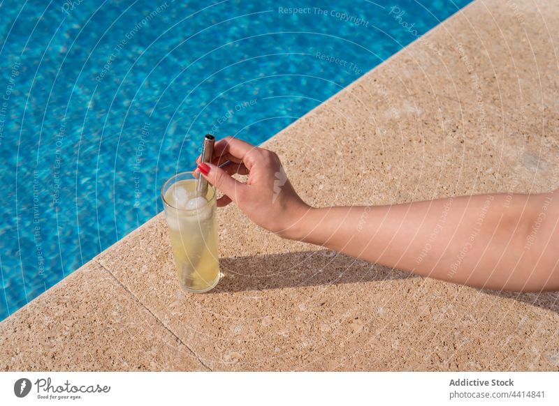 Crop Frau mit Glas kalten Cocktail am Pool Frauen Beckenrand Erfrischung Sommer trinken sonnig keine Verschwendung Getränk Wasser Sonnenlicht Eis Würfel cool