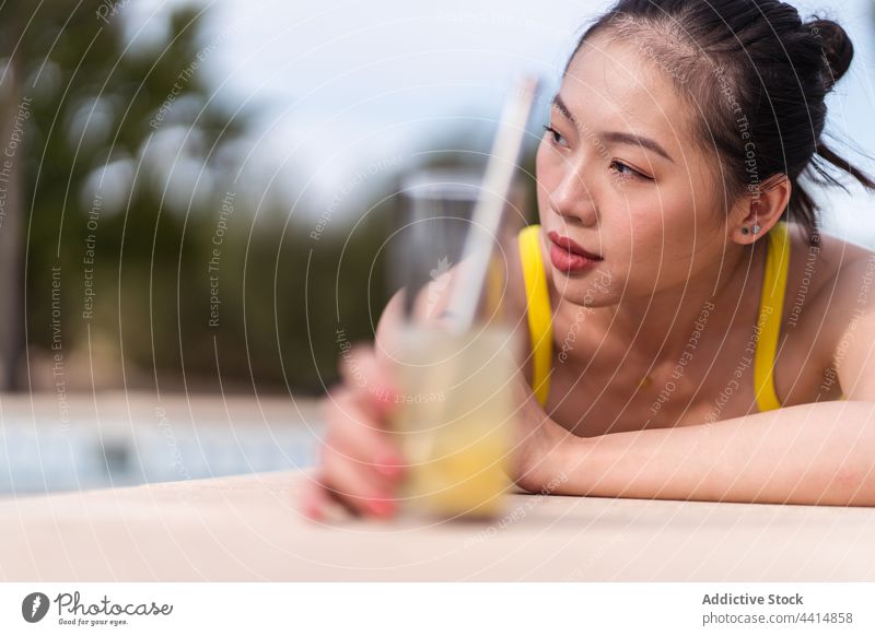 Ethnische Frau im Bikini beim Sonnenbaden am Pool im Sommer Beckenrand Bräune Lügen Urlaub Kälte Feiertag genießen ethnisch asiatisch gelb Farbe hell lebhaft