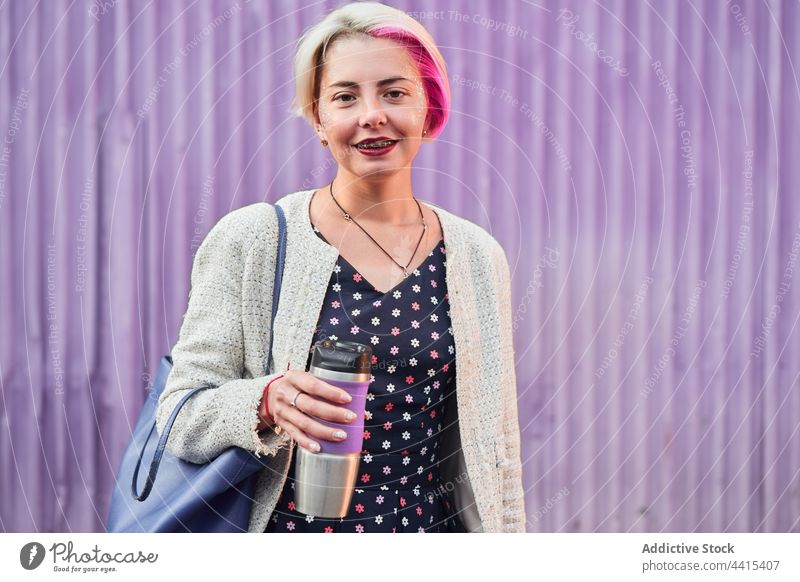 Stilvolle alternative Frau mit Kaffee im wiederverwendbaren Becher informell wiederverwenden Tasse umweltfreundlich Lächeln trinken Großstadt cool Straße