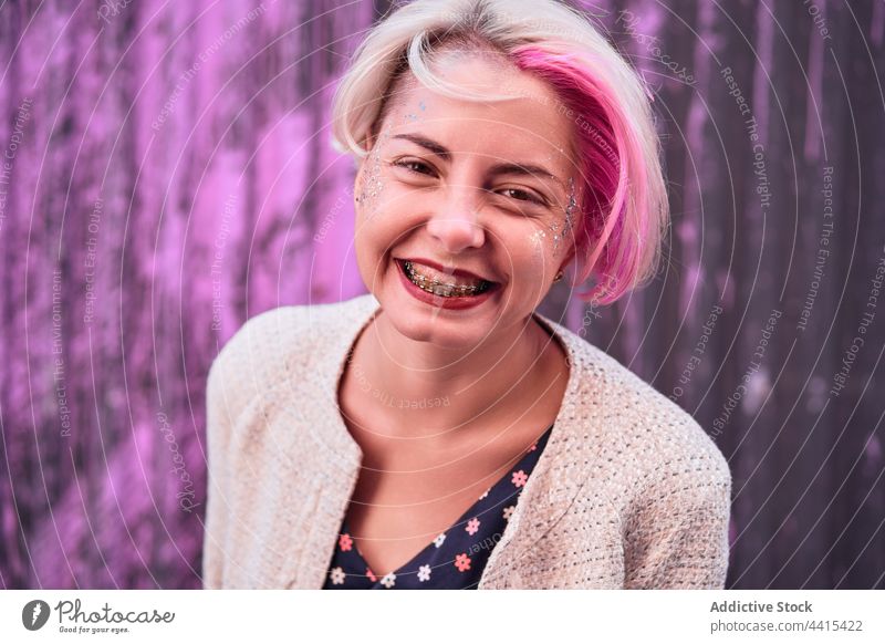 Informelle Frau mit gefärbtem Haar auf lila Hintergrund in der Stadt informell gefärbtes Haar Lächeln Vorschein Stil urban Großstadt trendy Zahnspange Subkultur