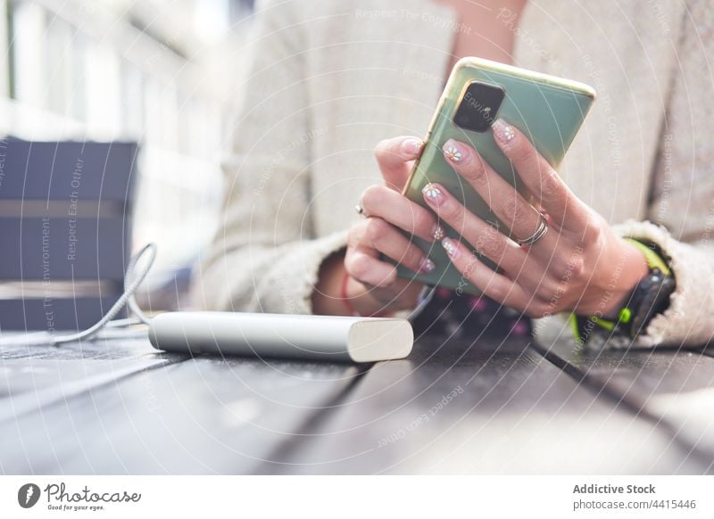 Anonyme, informelle Frau, die ein Mobiltelefon am Tisch eines Straßencafés benutzt benutzend Smartphone soziale Netzwerke Browsen Café Sommer alternativ
