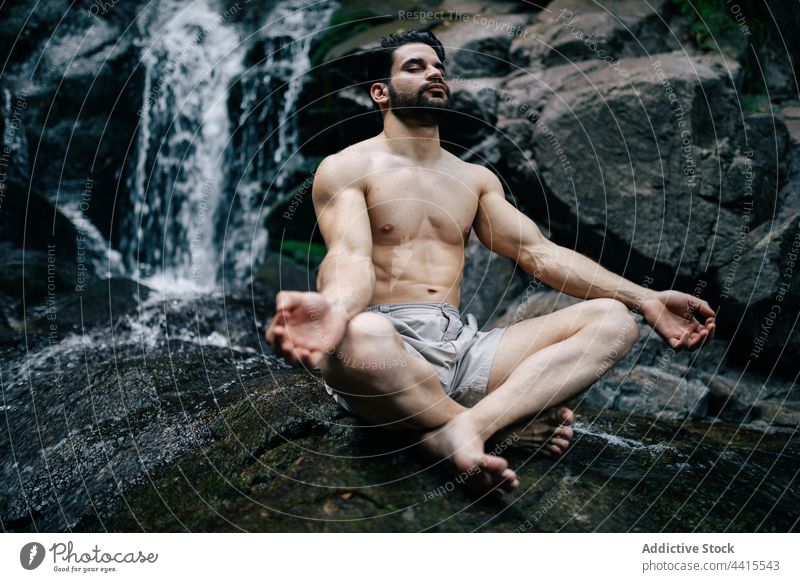 Gelassener Mann meditiert in Lotus-Pose in der Nähe eines Wasserfalls meditieren Yoga Natur Mudra Zen padmasana Achtsamkeit männlich Harmonie Sprit ruhig
