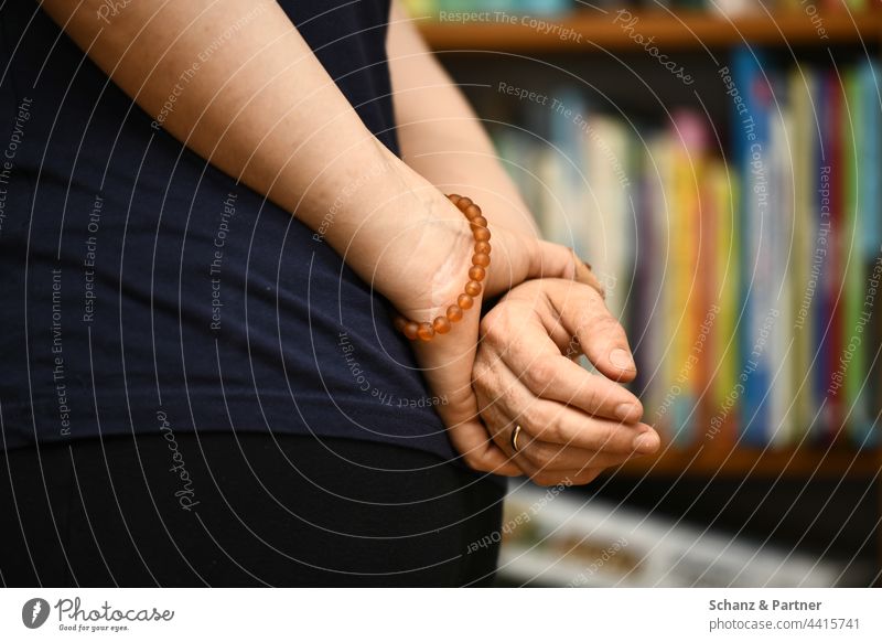 Hände hinterm Rücken verschränkt Hand Armband Schmuck warten Bücherregal Ehering Finger festhalten locker