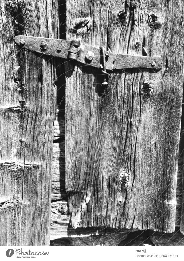 Rustikales, altertümliches, gebrochenes und mehrfach repariertes Scharnier, an einer Hütte. Beschläge rustikal historisch Holz Nägel Rost Verfall
