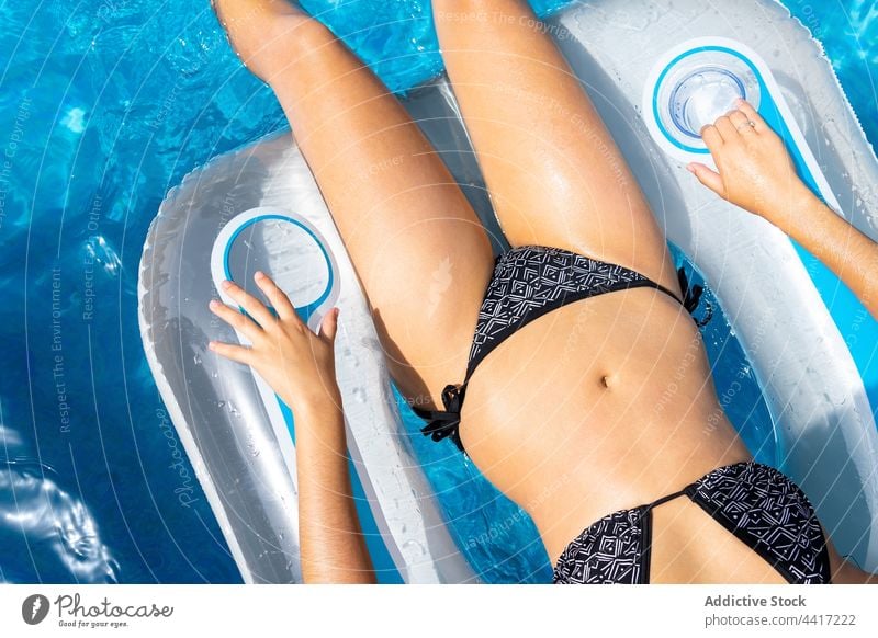 Schlanke Frau im Bikini beim Chillen im Pool aufblasbar Schlafmatratze Sonnenbad Sommer Kälte Urlaub Bräune Lügen sich[Akk] entspannen Resort Badeanzug