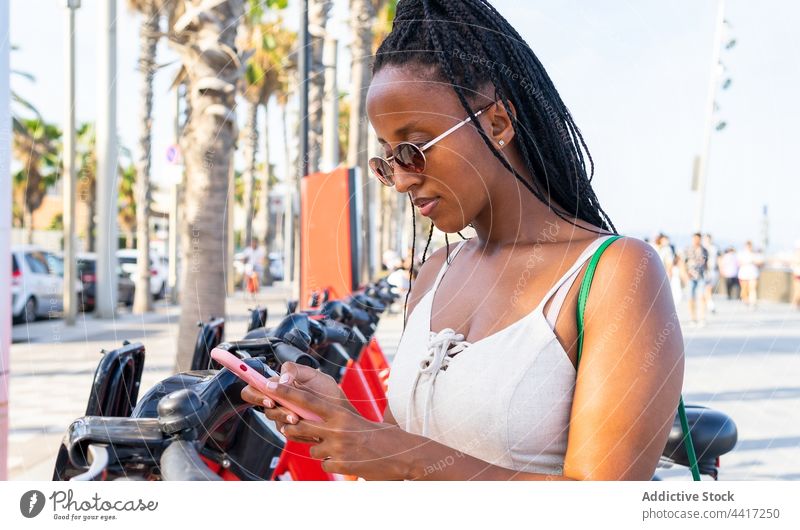 Schwarze Frau nutzt Smartphone, um in der Stadt ein Fahrrad zu mieten Miete Großstadt App benutzend teilen Funktelefon ethnisch schwarz Afroamerikaner