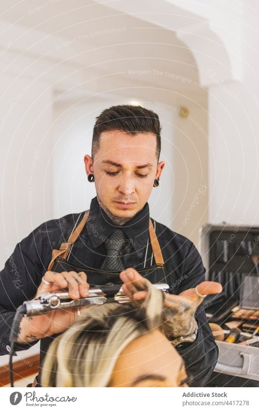 Männlicher Friseur lockt Haare einer Frau Mann Klient Salon Locken bügeln professionell Frisur Dienst Kunde Job Verfahren Arbeit Spezialist Meister blond