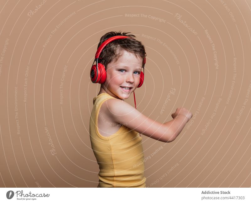Fröhliches Kind, das mit Kopfhörern Musik hört zuhören Gesang genießen Junge unterhalten Atelier Gerät Apparatur Klang Stil cool Vergnügen Talent Audio Kindheit