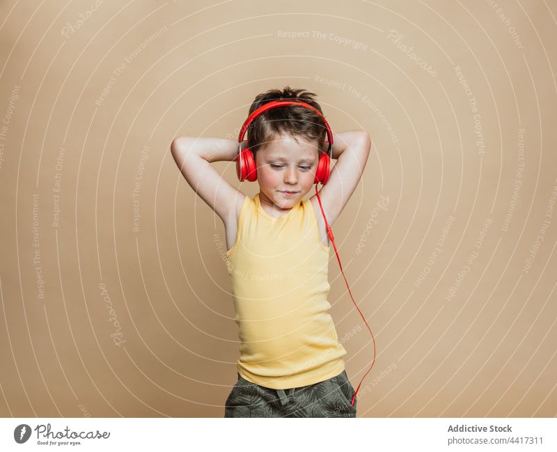 Kind hört Musik mit Kopfhörern im Studio Junge zuhören genießen sorgenfrei rot Farbe Gesang Audio modern Gerät Apparatur Melodie benutzend unterhalten Klang