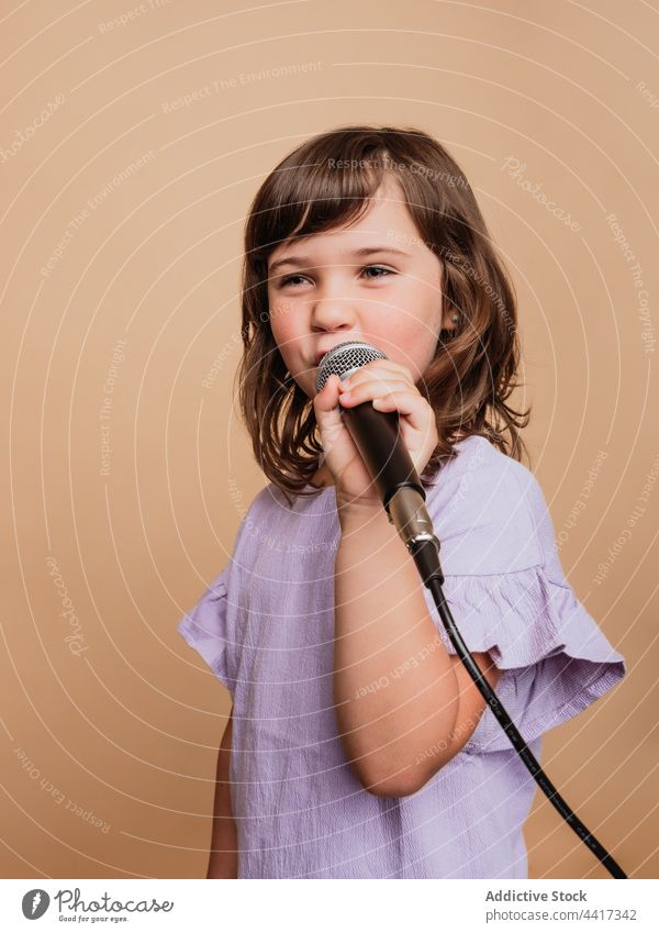 Lustiges Kind singt im Mikrofon im Studio singen Mädchen lustig Gesicht machen Comic Grimasse Gesang unterhalten Gesichtsausdruck cool Sänger Stil trendy Musik