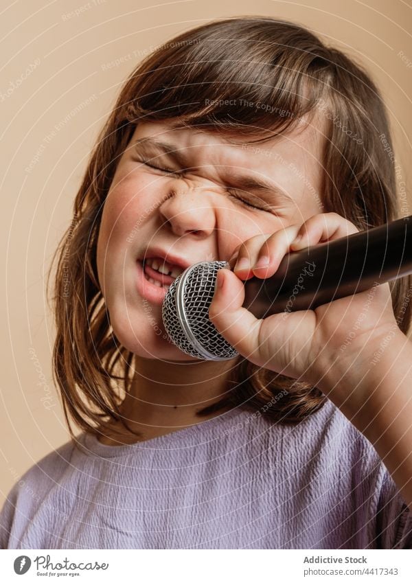 Lustiges Kind singt im Mikrofon im Studio singen Mädchen lustig Gesicht machen Comic Grimasse Gesang unterhalten Gesichtsausdruck cool Sänger Stil trendy Musik