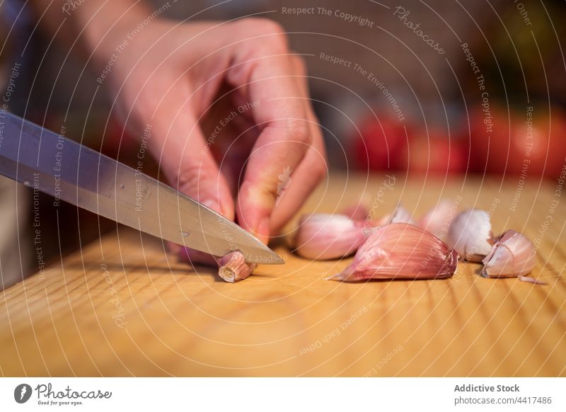 Eine Frau schneidet Knoblauch am Tisch geschnitten hacken Koch Schneidebrett Lebensmittel vorbereiten Küche Messer Bestandteil gesunde Ernährung frisch Hausfrau