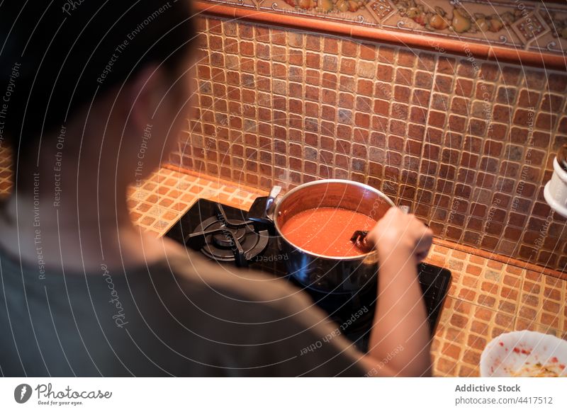 Crop-Frau bei der Zubereitung von Marinara-Soße aus Tomaten in einem Kochtopf Saucen Salz hinzufügen eingießen Herd vorbereiten kulinarisch Rezept Küche Speise