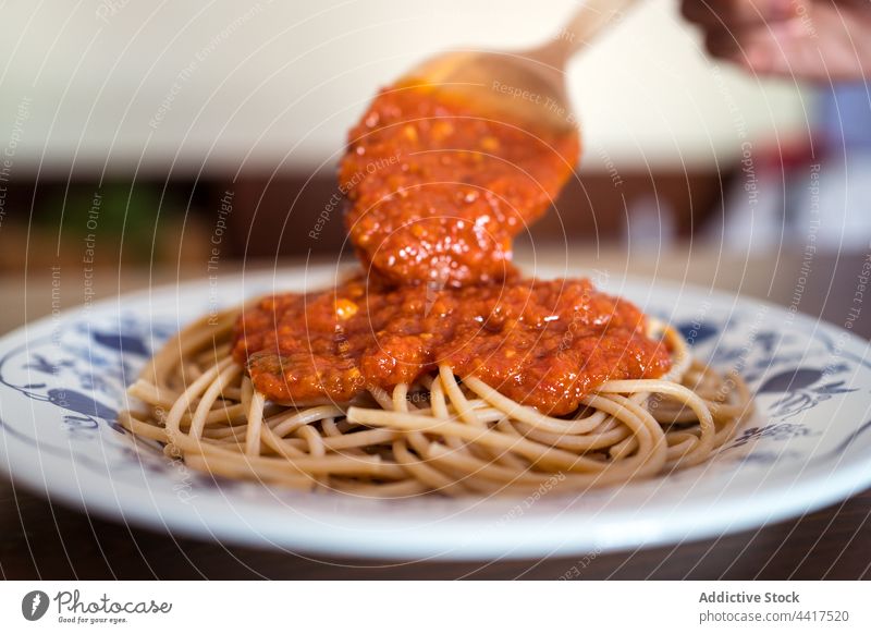 Crop Cook gibt Marinara-Sauce auf Spaghetti Saucen Tomate hinzufügen Koch Küchenchef Mittagessen Spätzle Mahlzeit geschmackvoll Lebensmittel lecker Speise