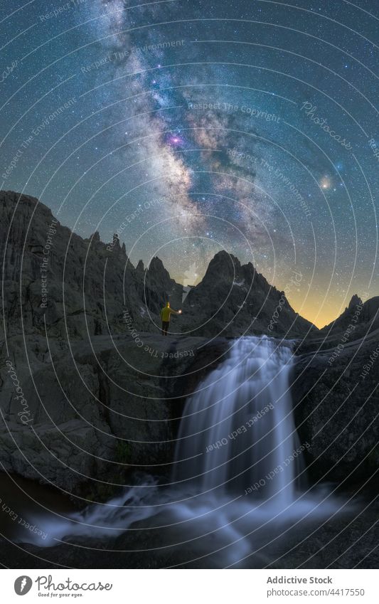 Unbekannter Tourist bewundert Wasserfall unter Sternenhimmel mit Milchstraße Person Milchstrasse Nacht wild sternenklar felsig Landschaft Natur rau Umwelt