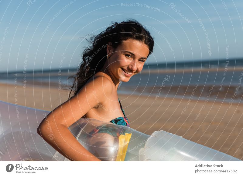Fröhliche Frau, die im Sommer am Sandstrand spazieren geht Strand Urlaub sonnig aufblasbar Schlafmatratze Spaziergang Lächeln Küste Glück Ufer Feiertag