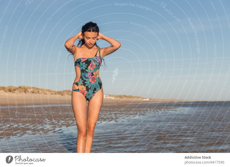 Frau im Badeanzug am Meeresufer im Sommer Strand MEER Urlaub genießen Lächeln Feiertag heiter Badebekleidung Sommerzeit Sonnenlicht sonnig Küste Ufer nass