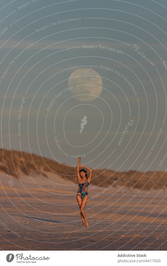 Anmutige Frau am Meeresufer im Sonnenuntergang stehend Strand Abend Sommer Badeanzug Gelassenheit Dämmerung Sand Ufer Mond Himmel Badebekleidung idyllisch
