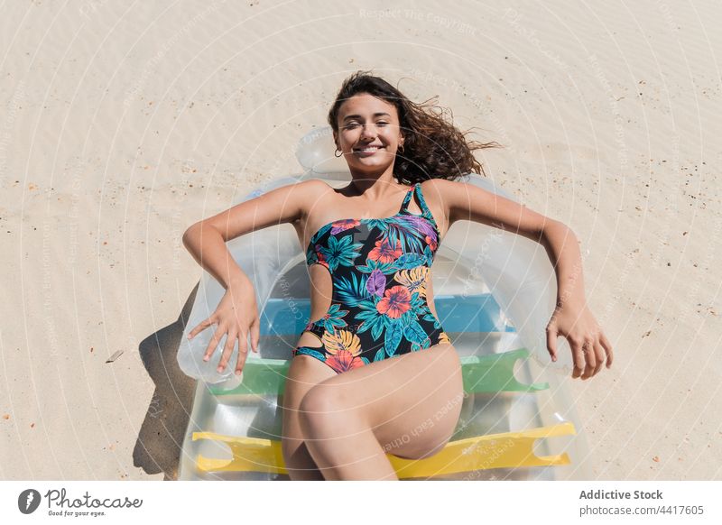 Fröhliche Frau beim Sonnenbaden auf einer aufblasbaren Matratze am Strand Bräune Sommer Urlaub Schlafmatratze Badeanzug Feiertag sich[Akk] entspannen Lügen