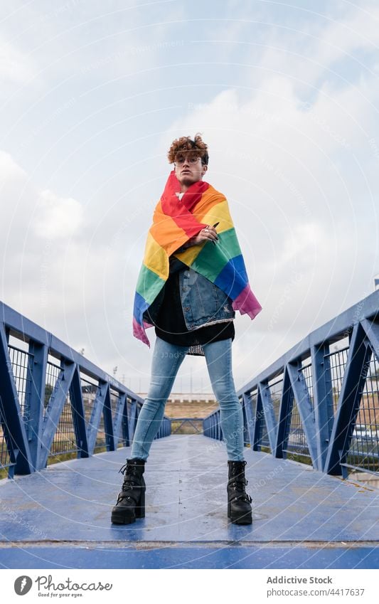 Schwuler Mann mit LGBT-Flagge auf Brücke Homosexualität Regenbogen Fahne lgbt schwul Stolz Freiheit Großstadt Stil männlich trendy stehen Arme hochgezogen