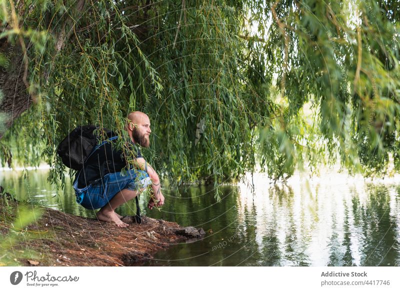 Mann mit Rucksack sitzt am Ufer eines Sees Natur Umwelt Landschaft Sommer Baum Wasser männlich Küste Reisender Ausflug Windstille Tourismus sitzen friedlich
