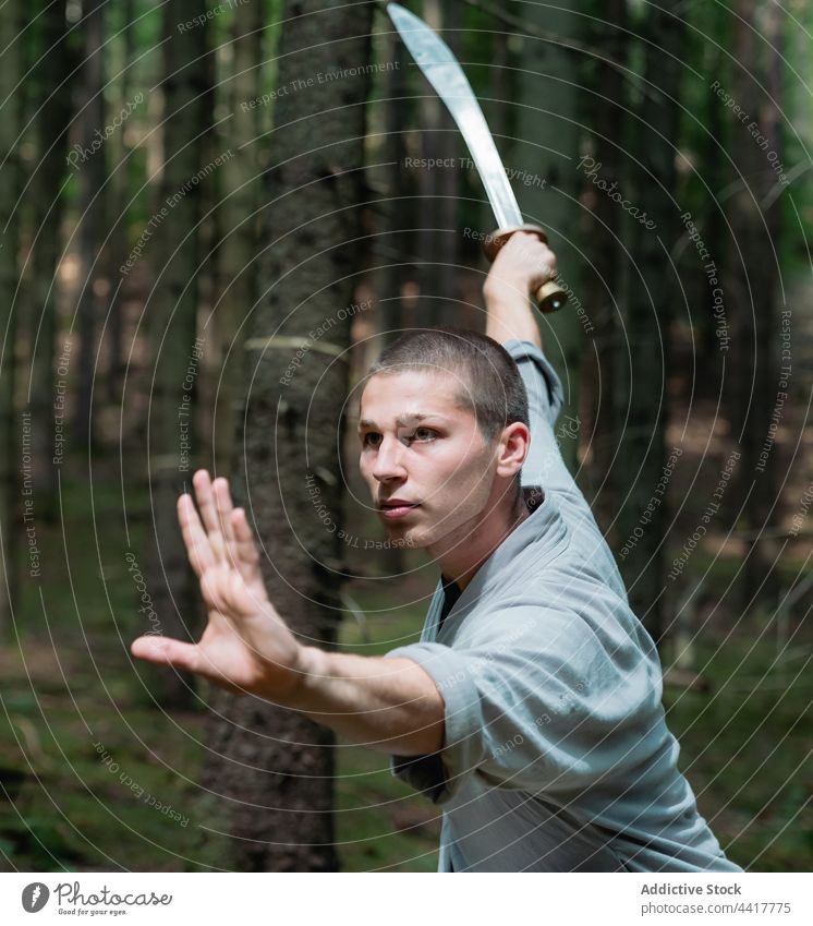 Kung-Fu-Krieger beim Üben mit dem Schwert Mann Wald Training Haltung Technik Tradition üben männlich kämpferisch Gleichgewicht stark Waffe Ausfallschritt
