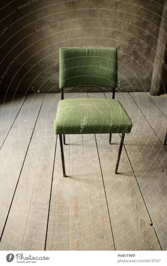 Grüner Stuhl auf einem Holzboden von der Seite beleuchtet grün Diele Dielenboden Innenausstattung Raum Wand alt Staub staubig sitzen Sitz innen Stoff