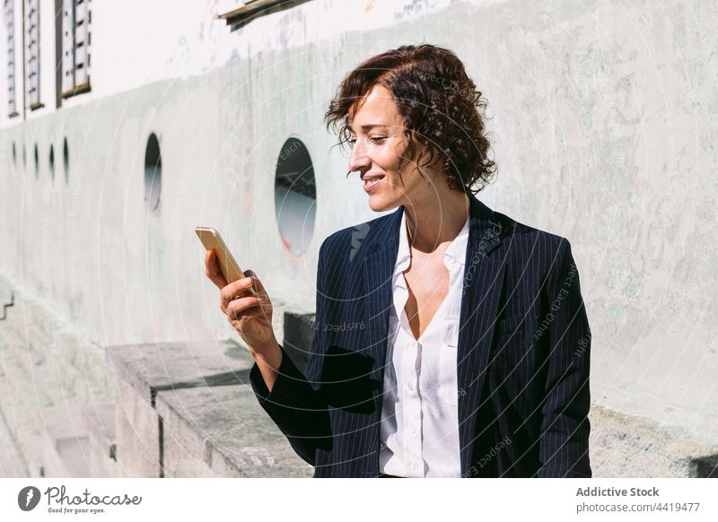 Lächelnde Frau in formeller Kleidung beim Surfen auf dem Smartphone Exekutive benutzend positiv Browsen formal Business Anschluss professionell Gerät