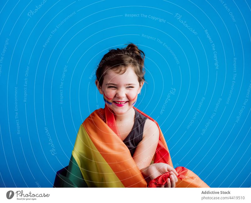 Fröhliches Mädchen hält bunte Flagge Kind farbenfroh Kindheit Farbe wenig Lächeln lebhaft niedlich Zahnfarbenes Lächeln pulsierend Streifen mehrfarbig