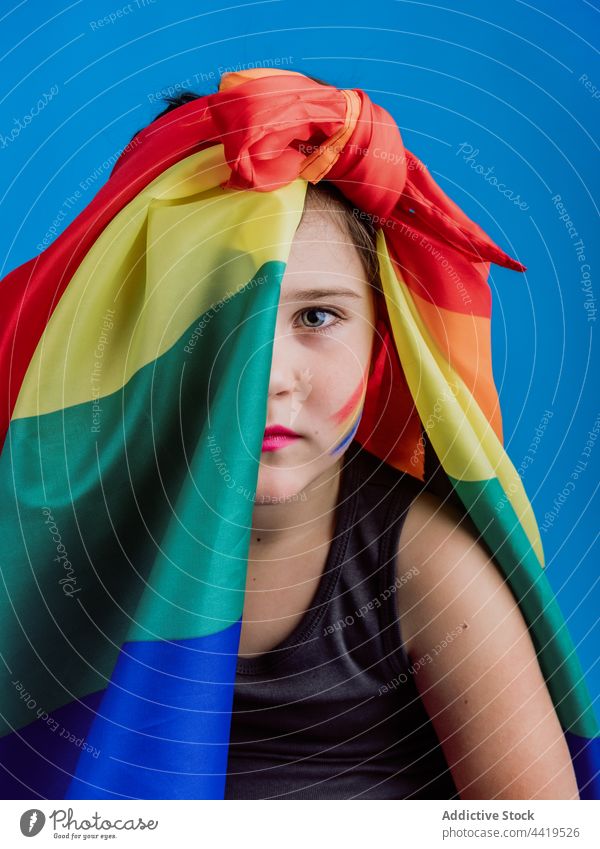 Weibliches Kind mit Regenbogenflagge im Gesicht Porträt Mädchen farbenfroh Menschliches Gesicht Deckung Farbe Fahne lebhaft hell Konzept Symbol niedlich kreativ
