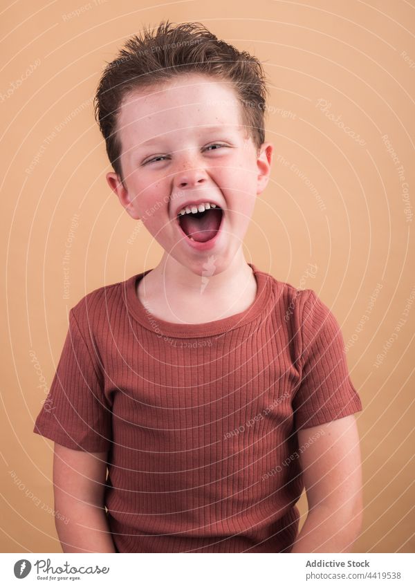Lächelnder Junge im T-Shirt auf beigem Hintergrund zufrieden freundlich herzlich genießen angenehm Art charmant Porträt Kindheit sanft Angebot Stoff heiter