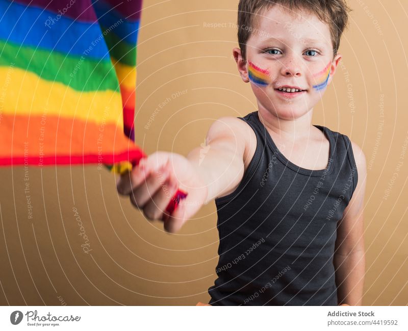 Lächelnder Junge mit Regenbogenflagge und gestreiftem Make-up Fahne lgbtq Stolz Gleichstellung rechts Freiheit Porträt Toleranz Solidarität Spektrum Konzept