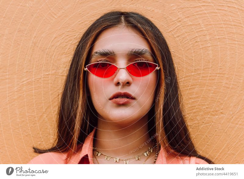 Porträt einer Frau mit modischer Sonnenbrille selbstbewusst trendy modern Stil cool in die Kamera schauen Individualität lange Haare brünett feminin Vorschein