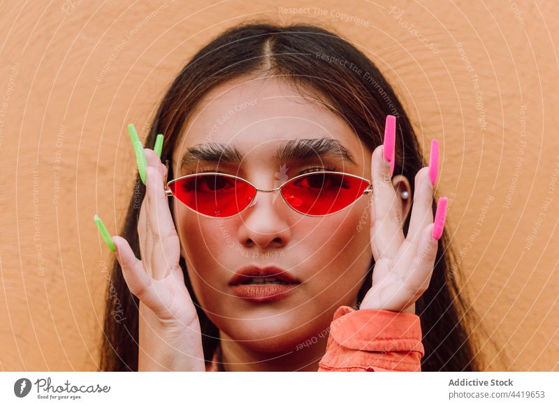 Stilvolle Frau, die eine stilvolle Sonnenbrille aufsetzt Porträt selbstbewusst angezogen trendy modern cool Lange Nägel in die Kamera schauen Individualität