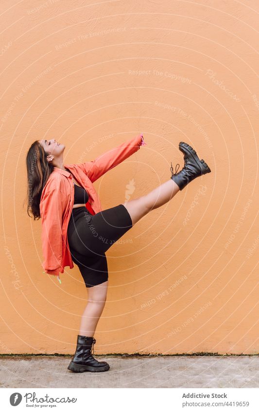 Energetische Frau macht Kick in der Nähe gemalt Wand heiter sich[Akk] bewegen Stil Körperhaltung cool Spaß Tanzen Energie Vergnügen positiv Augen geschlossen