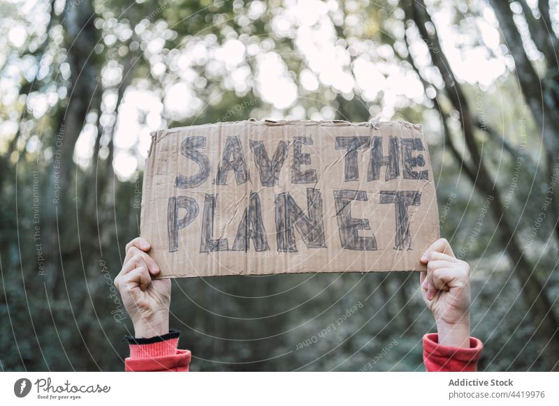 Anonymes Mädchen mit "Save The Planet"-Aufschrift auf Kartonstück den Planeten retten bewahren Natur Ökologie konservieren Wald Porträt Kofferraum Baum