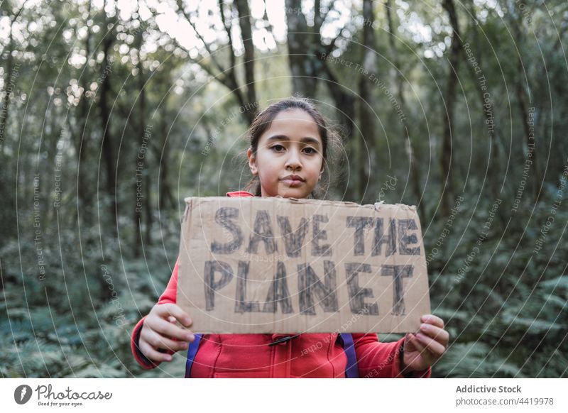 Ethnisches Mädchen mit "Save The Planet"-Aufschrift auf einem Stück Karton den Planeten retten bewahren Natur Umwelt Ökologie konservieren Wald Porträt