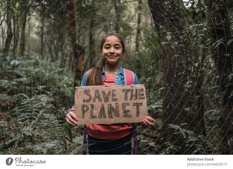 Ethnisches Mädchen zeigt Save The Planet-Titel im Sommerwald den Planeten retten Wald Natur Umwelt behüten bewahren konservieren Welt Porträt abstützen Lächeln