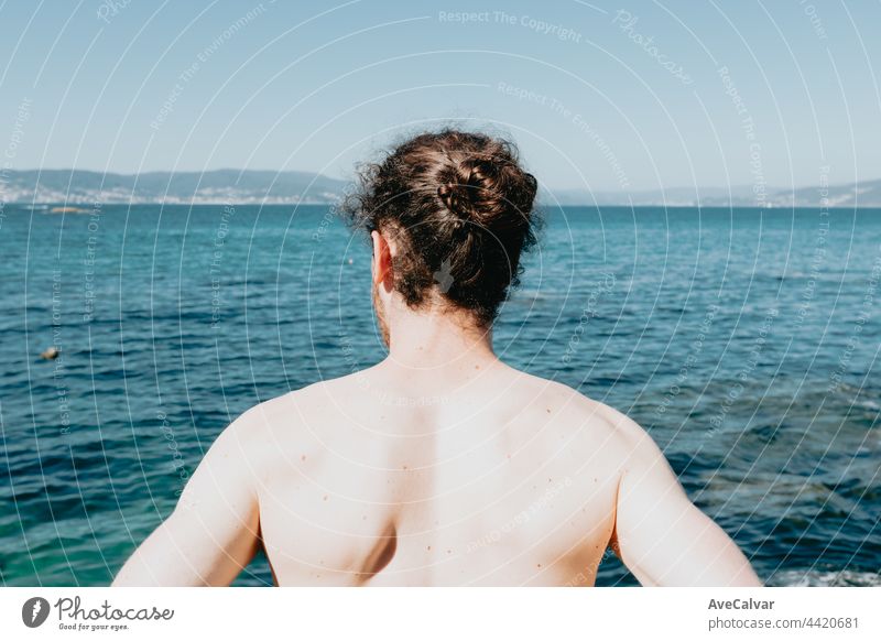 Der Rücken eines jungen Mannes vor dem Ozean während eines sonnigen Tages mit Vertrauen, Freiheit und Zukunftskonzepte, Kopie Raum, Sommer, Urlaub horizontal