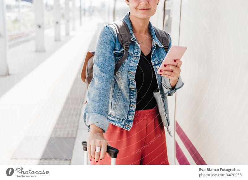 Nahaufnahme von Backpacker kaukasische Frau hält Gepäck am Bahnhof bereit, den Zug zu fangen. Sie hält ihr Handy und benutzt eine App. Reisen Konzept